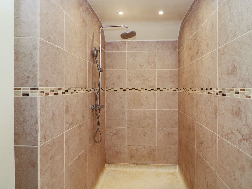 A shower with wall tiles and a shower head at Ten Gables in Driffield