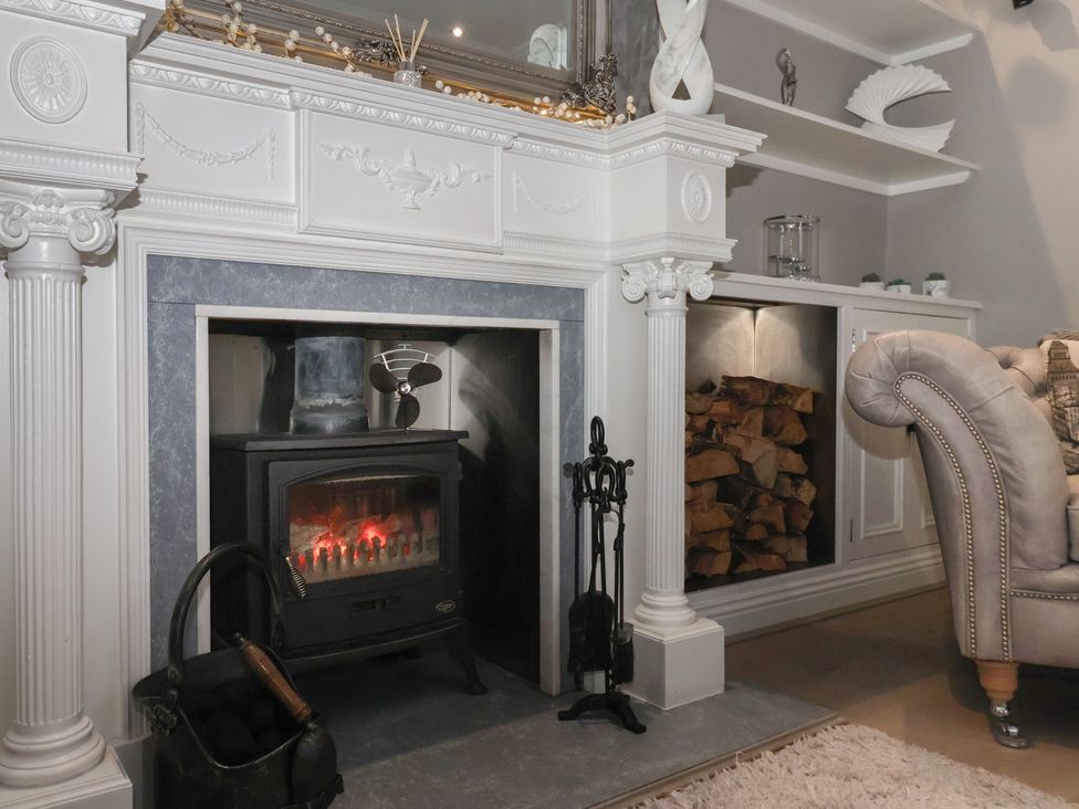 A living room with a fireplace and armchair at Ten Gables in Driffield