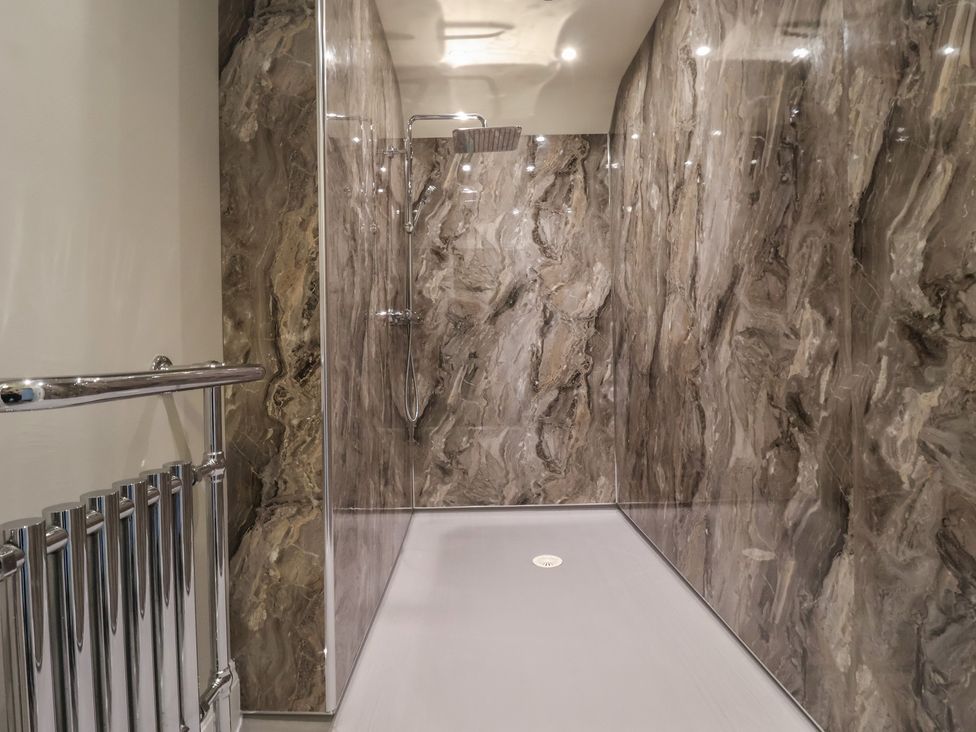 A shower area with marble walls and chrome fittings at Ten Gables in Driffield
