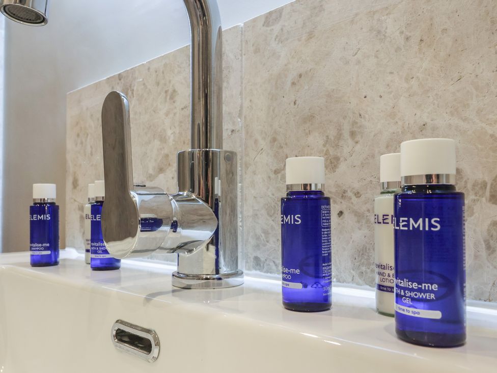 A bathroom sink with a faucet and bottles of shampoo and shower gel at Ten Gables in Driffield