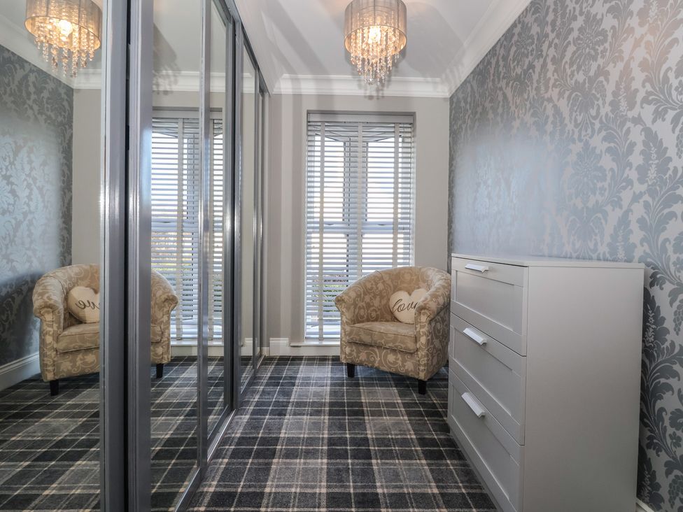 A bedroom with an armchair and dresser at Ten Gables in Driffield