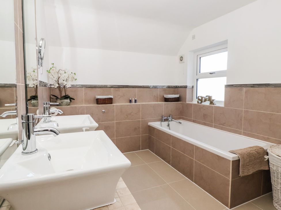 A bathroom with double sinks and a bathtub at Ten Gables in Driffield