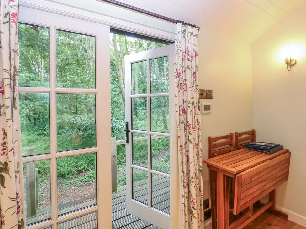 A room with a table and chairs leading to an outdoor area at Woodlands Retreat Shepherd's Hut Brundish near Laxfield