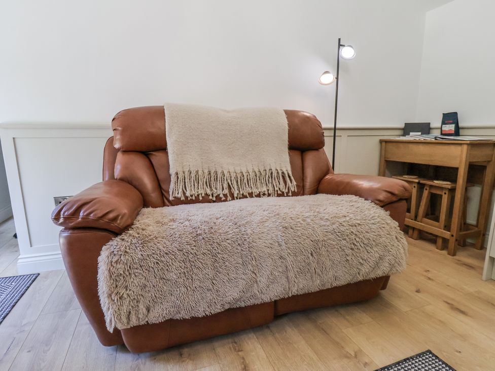 A sofa with a throw blanket and a lamp at Roe Deer Lodge Littlebeck near Sleights