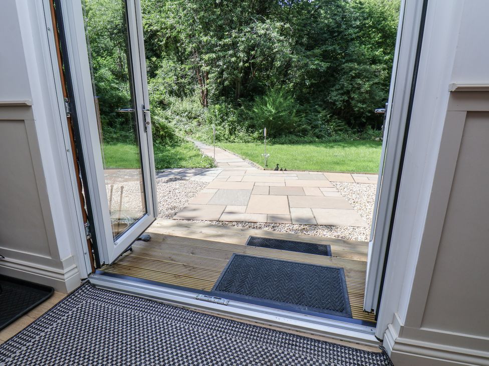 An entrance with a door open to a pathway and grassy area at Roe Deer Lodge Littlebeck near Sleights