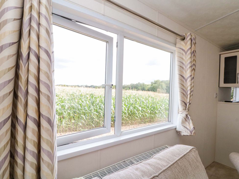 A living room with a window overlooking a field at The Cosy Caravan Islebeck near Thirsk