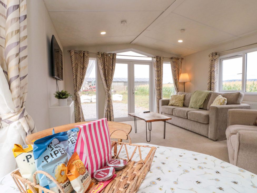 A living room with a sofa and snacks on a table at The Cosy Caravan in Islebeck near Thirsk