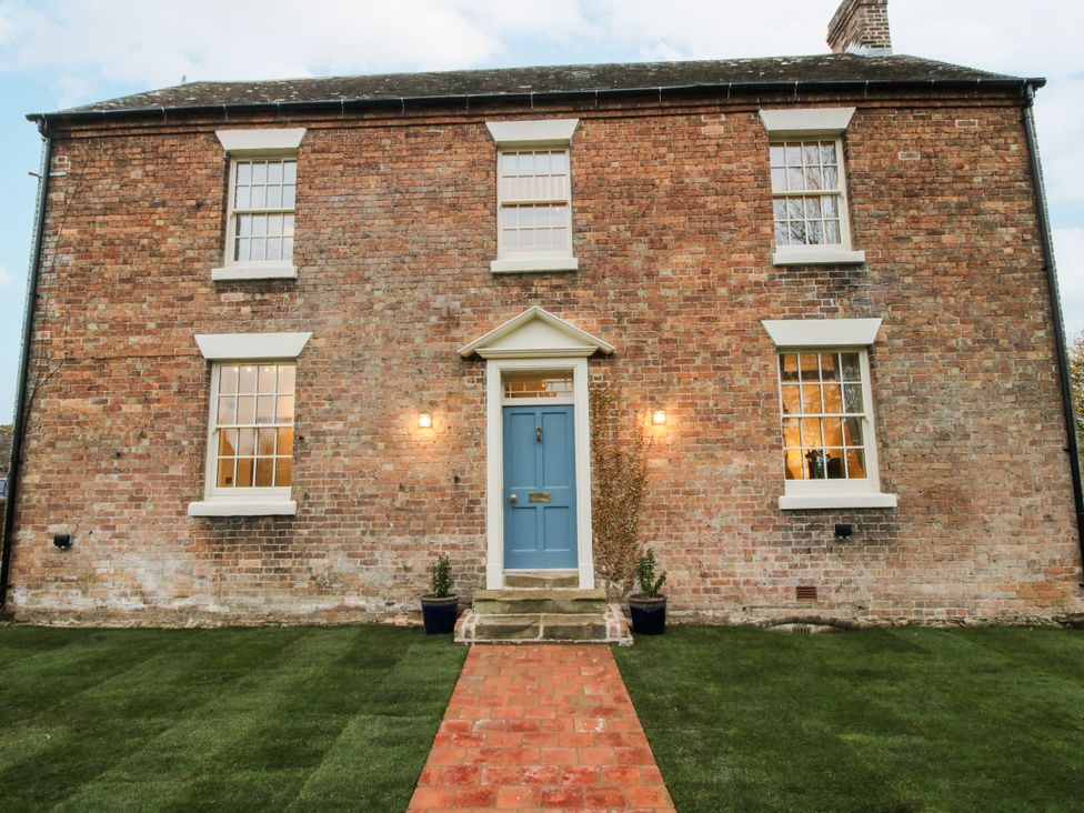 A brick house with a blue front door and garden at Highfields Farm in Church Preen near Much Wenlock