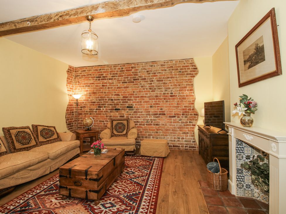 A living room with a brick wall and wooden coffee table at Highfields Farm Church Preen near Much Wenlock
