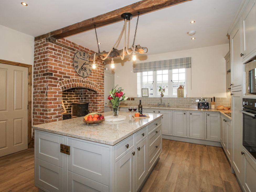 A kitchen with a large island and brick wall at Highfields Farm Church Preen near Much Wenlock