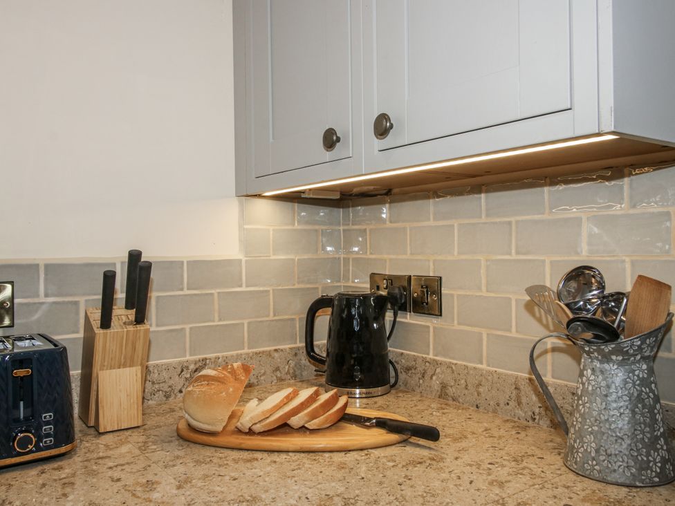 A kitchen with a toaster, kettle, and sliced bread on a cutting board at Highfields Farm, Church Preen near Much Wenlock
