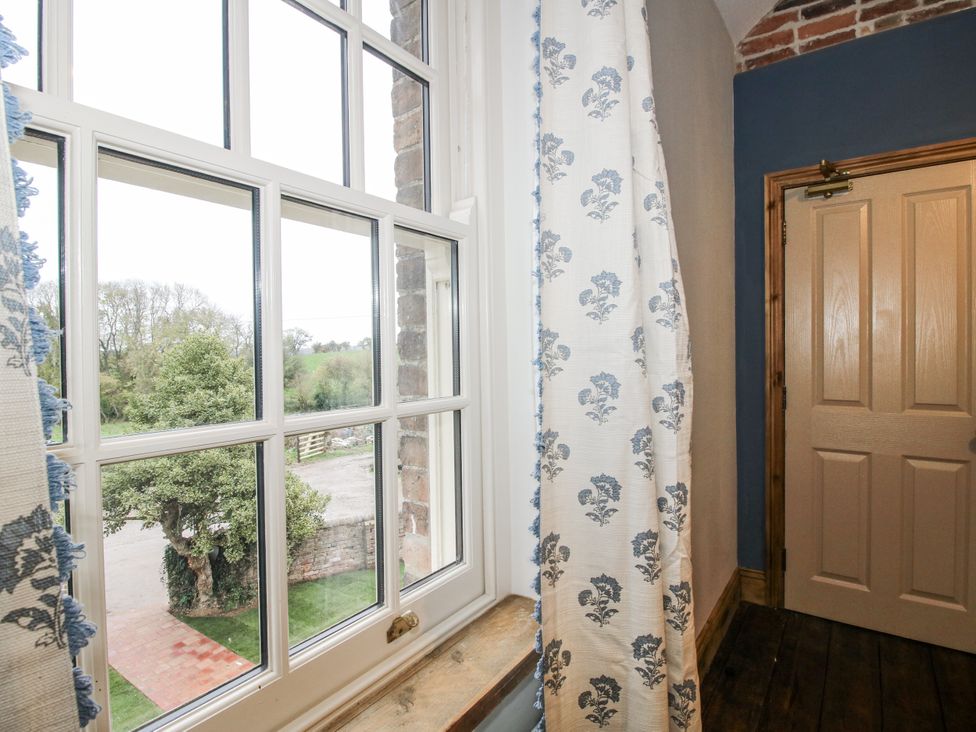 A window with curtains and a door at Highfields Farm Church Preen near Much Wenlock