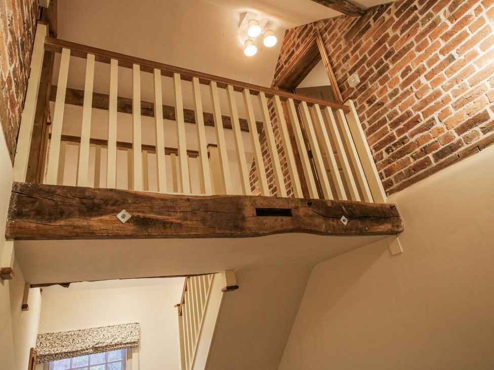 A staircase with a wooden railing and brick wall at Highfields Farm Church Preen near Much Wenlock