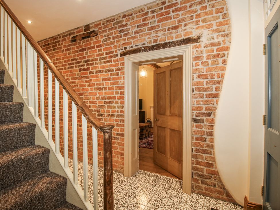 A hallway with a staircase and brick wall at Highfields Farm Church Preen near Much Wenlock