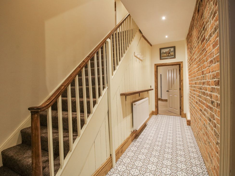A hallway with a staircase and brick wall at Highfields Farm Church Preen near Much Wenlock
