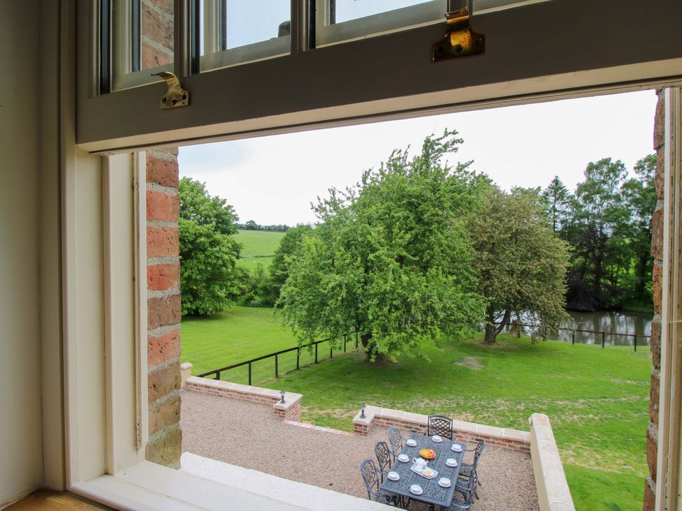 A view from a window overlooking a garden with an outdoor table and trees at Highfields Farm Church Preen near Much Wenlock