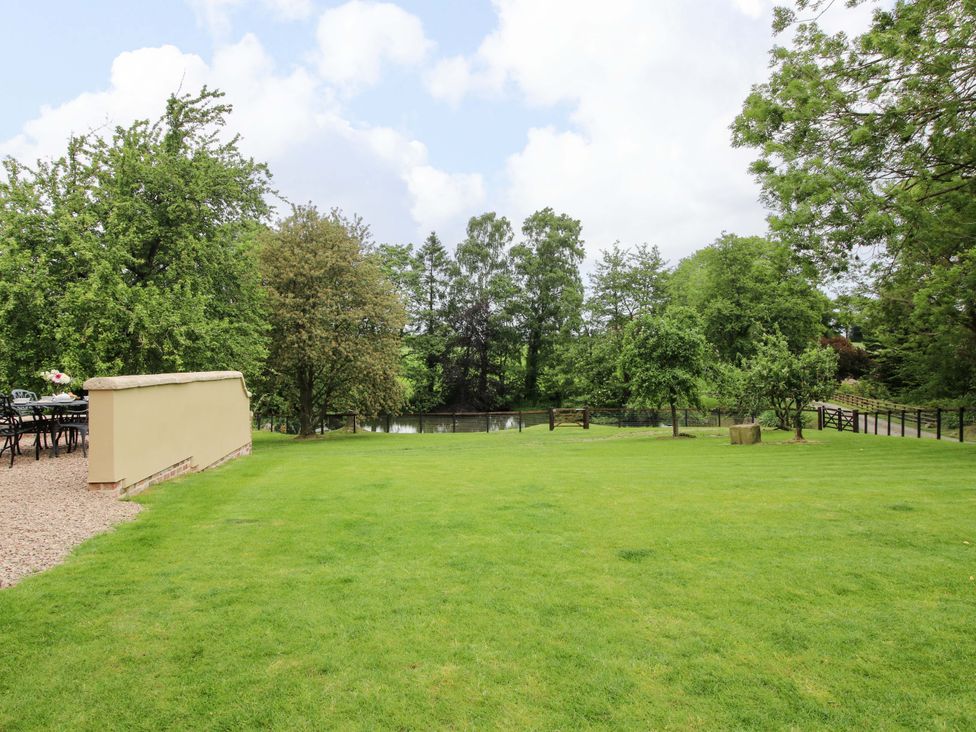 A garden with grass, trees, and a pond at Highfields Farm near Church Preen