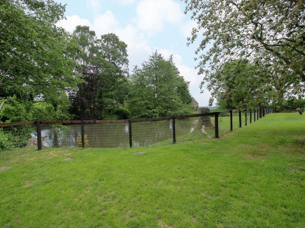 A view of a fenced area with water and trees at Highfields Farm in Church Preen near Much Wenlock