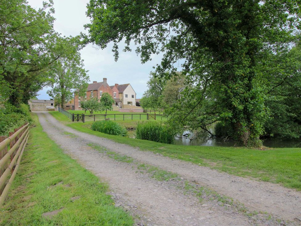 A house and trees near a river at Highfields Farm Church Preen near Much Wenlock
