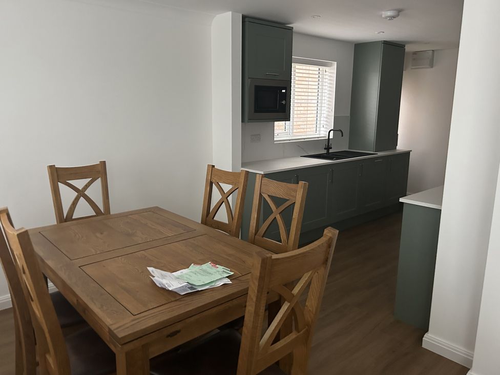 A dining room with a table and chairs adjacent to a kitchen at 40 Gloddaeth View in Llandudno