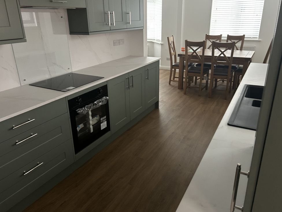 A kitchen with cabinets and a dining table at 40 Gloddaeth View Llandudno