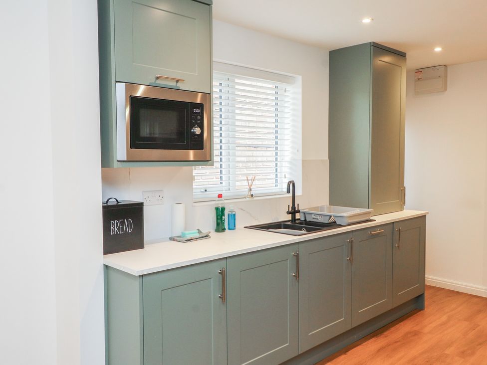 A kitchen with a sink and microwave at 40 Gloddaeth View in Penrhyn Bay