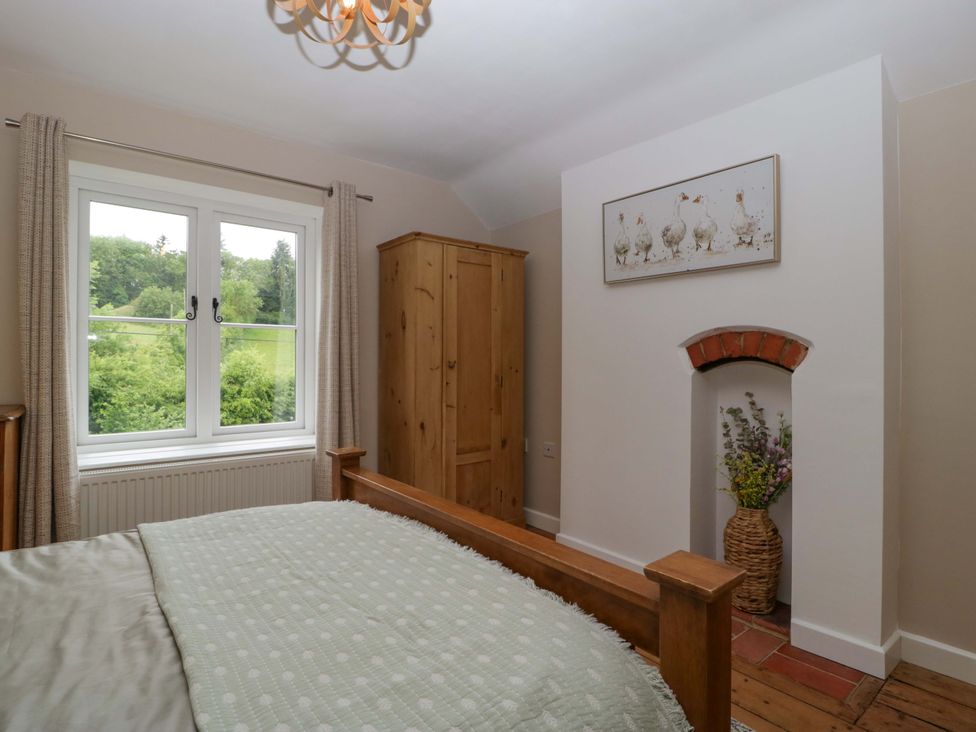 A bedroom with a bed, wardrobe, and window at 2 Loxter Villas, Wellington Heath near Ledbury