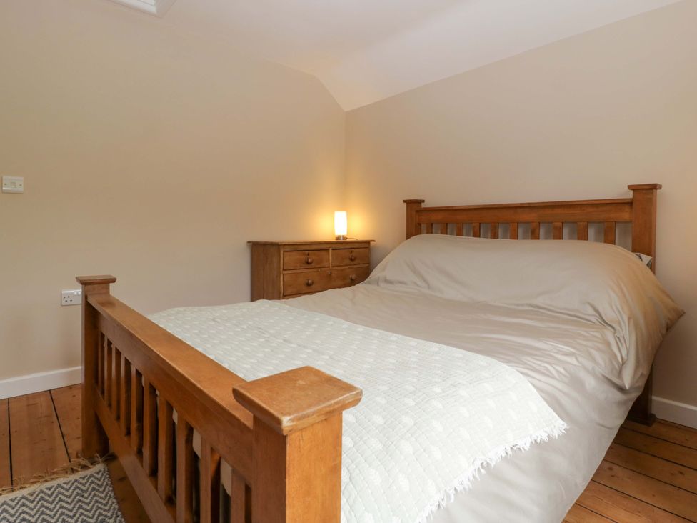 A bedroom with a wooden bed and chest of drawers at 2 Loxter Villas Wellington Heath near Ledbury