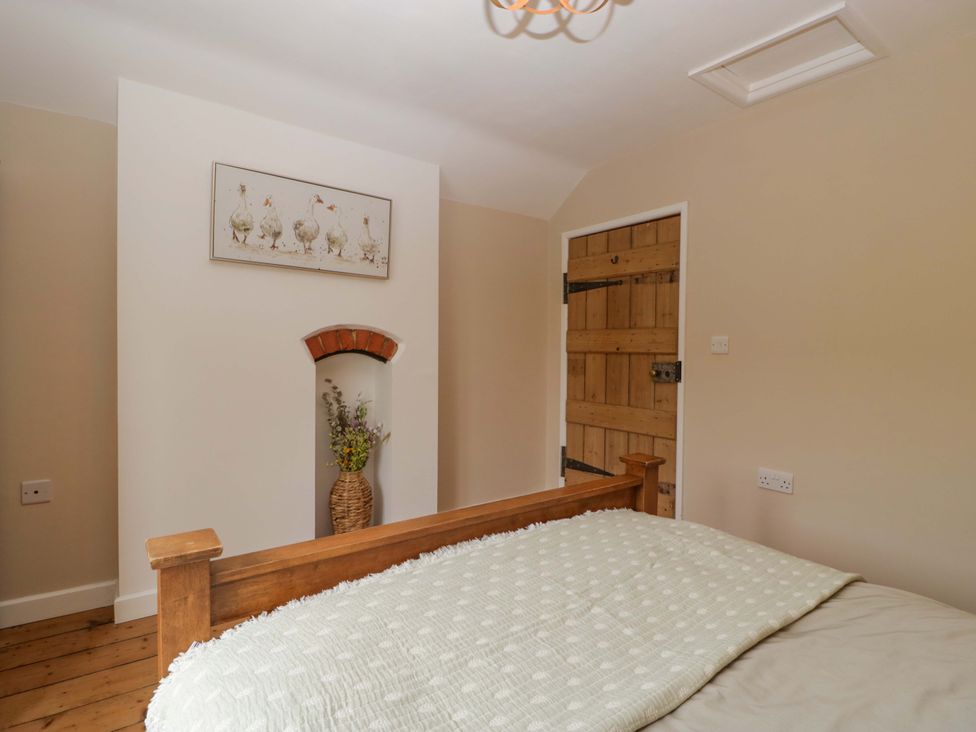 A bedroom with a bed and wooden door at 2 Loxter Villas in Wellington Heath near Ledbury