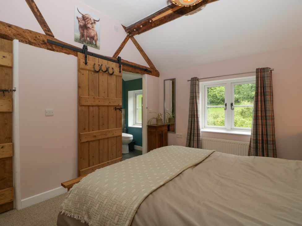 A bedroom with a bed and wooden door at 2 Loxter Villas Wellington Heath near Ledbury