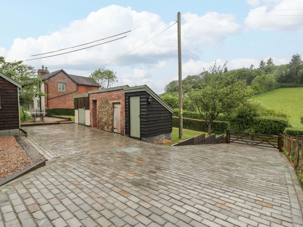 An outdoor area with houses, a paved driveway, and trees at 2 Loxter Villas in Wellington Heath near Ledbury