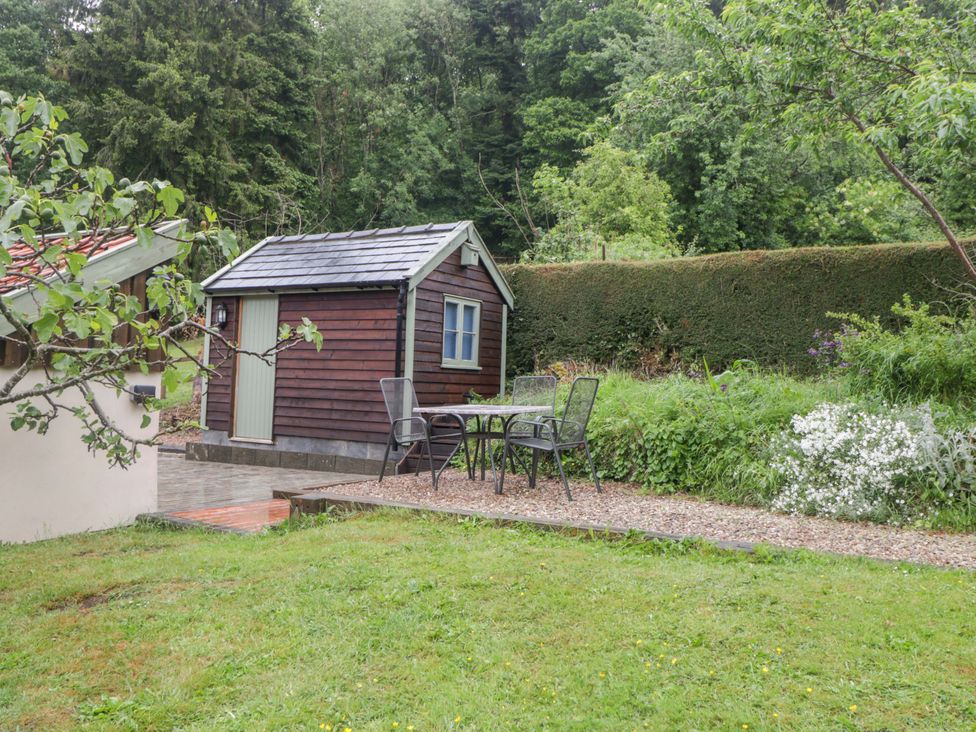 A shed with chairs and a table on a path surrounded by grass at 2 Loxter Villas Wellington Heath near Ledbury