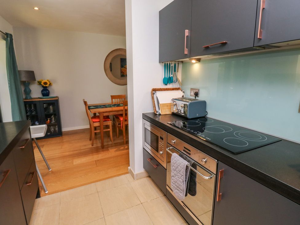 A kitchen with appliances and dining area at 8 Pottery Cottages