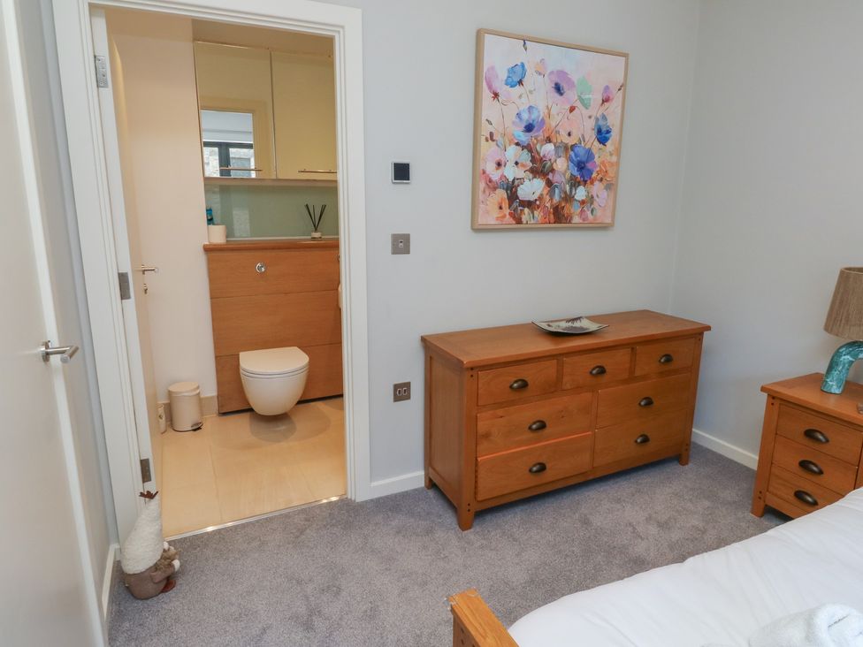 A bedroom with a wooden dresser and bathroom in view at 8 Pottery Cottages