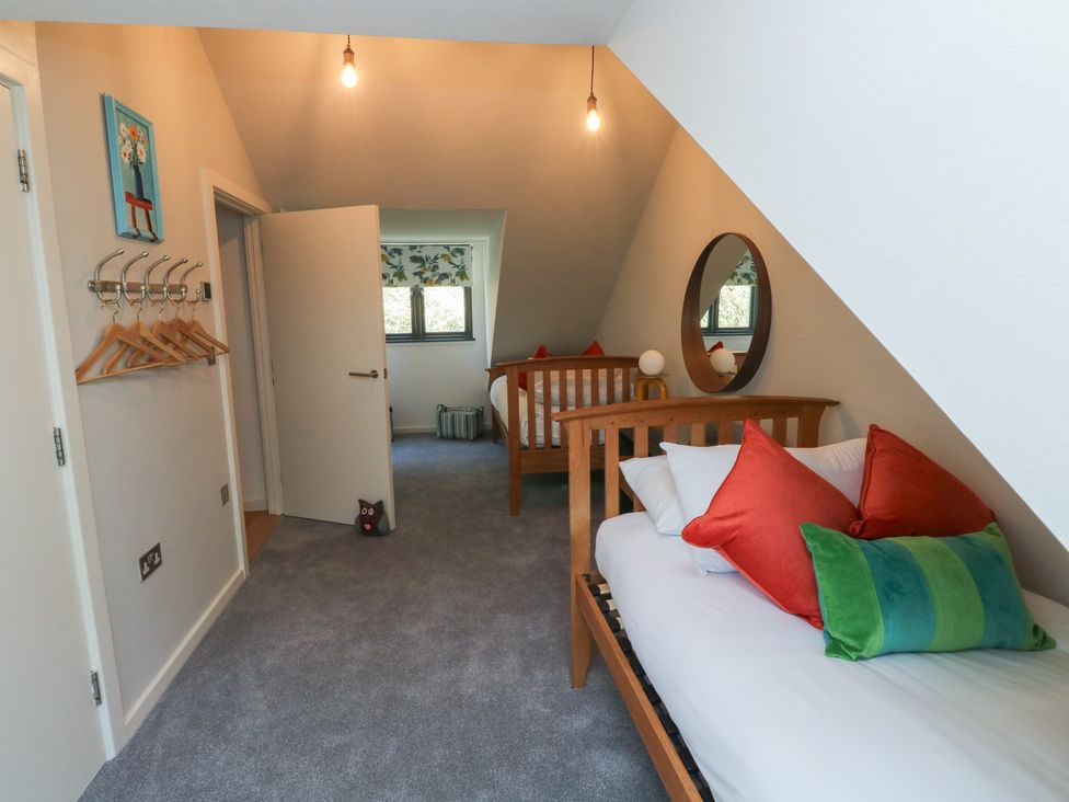 A bedroom with two beds and a coat rack at 8 Pottery Cottages