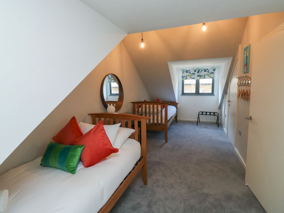 A bedroom with two beds and a mirror at 8 Pottery Cottages in 