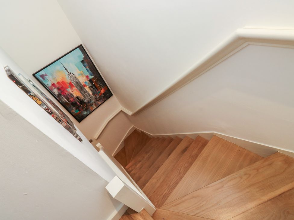 A staircase with wooden steps and a painting on the wall at 8 Pottery Cottages