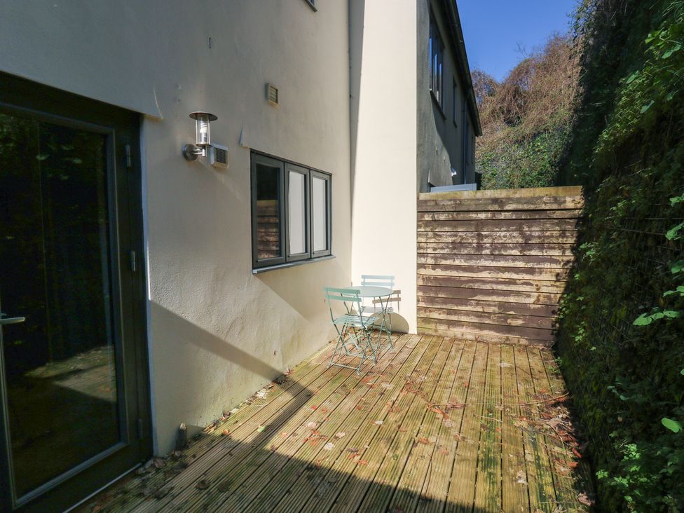 A garden area with a wooden deck and chairs at 8 Pottery Cottages