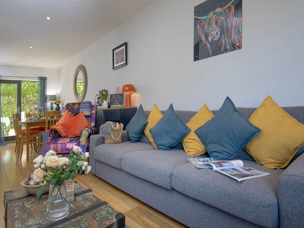 A living room with a sofa and dining area at Mariners Retreat, 8 Pottery Cottages in Dartmouth