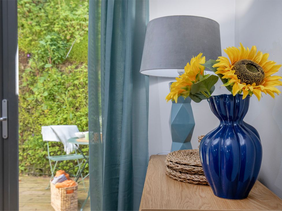A vase with sunflowers and a lamp on a table at Mariners Retreat, 8 Pottery Cottages, Dartmouth