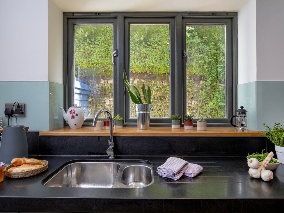 A kitchen with a sink, plants and cooking utensils at Mariners Retreat, 8 Pottery Cottages Dartmouth