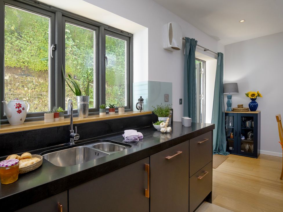 A kitchen with a sink and cabinets at Mariners Retreat, 8 Pottery Cottages in Dartmouth