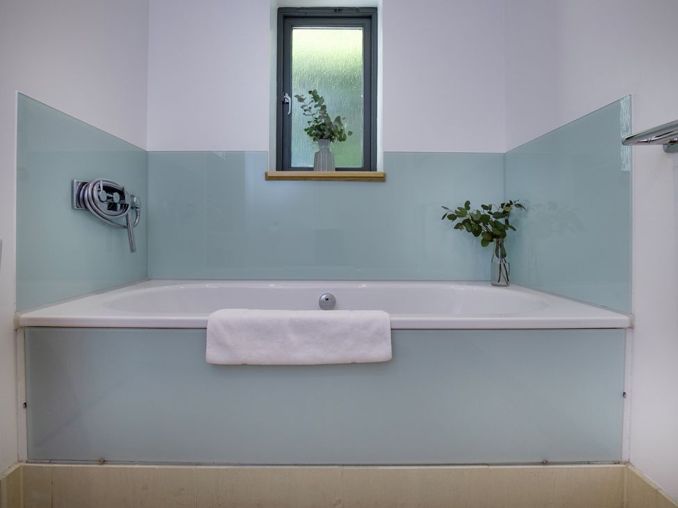 A bathroom with a bathtub and a window at Mariners Retreat, 8 Pottery Cottages in Dartmouth