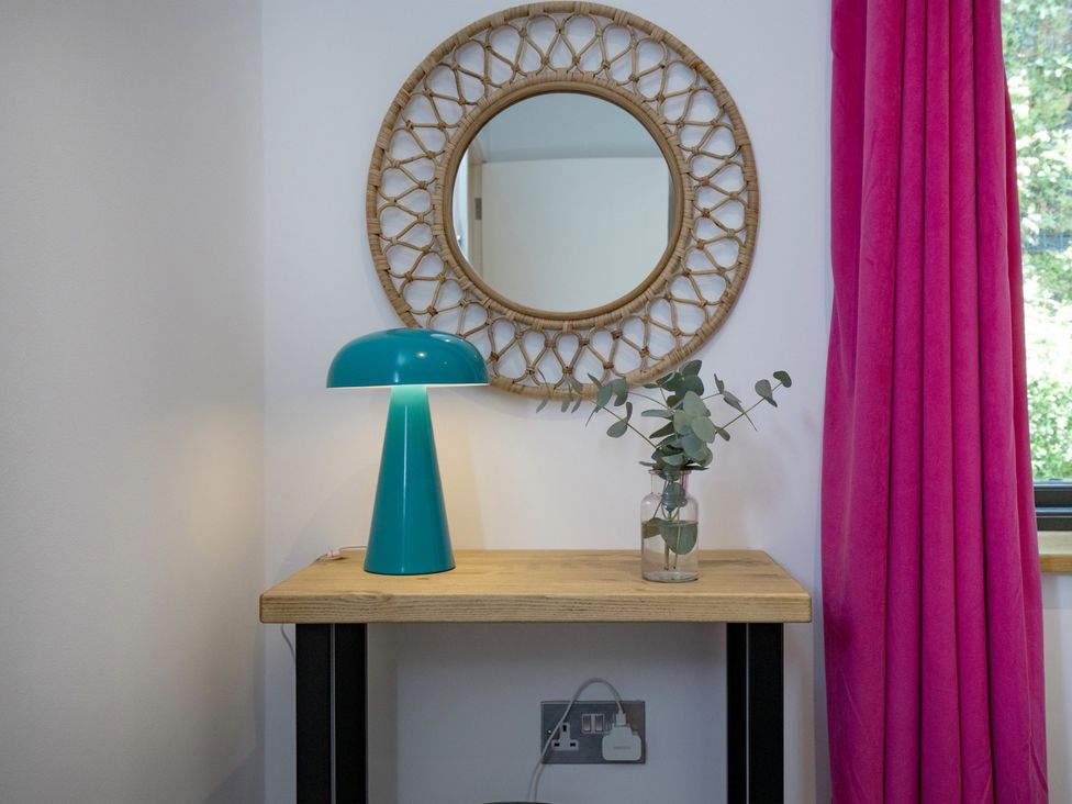 A living room with a lamp, table, mirror, and plant at Mariners Retreat, 8 Pottery Cottages, Dartmouth