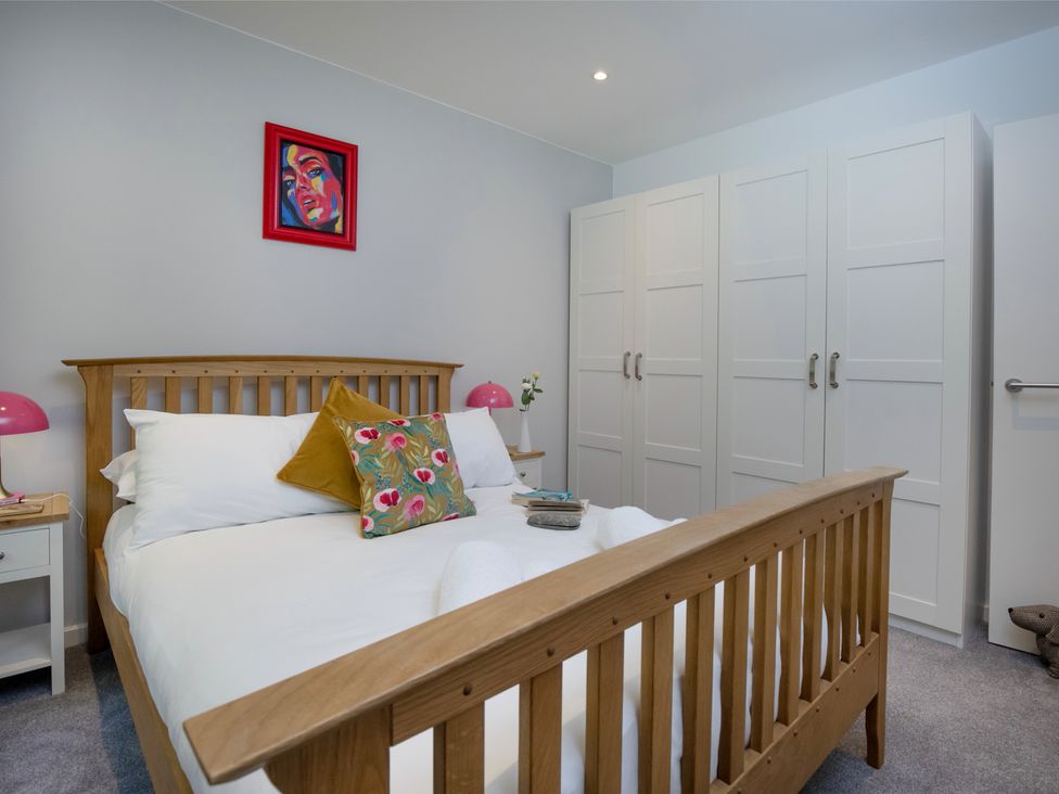 A bedroom with a bed and wardrobe at Mariners Retreat, 8 Pottery Cottages Dartmouth