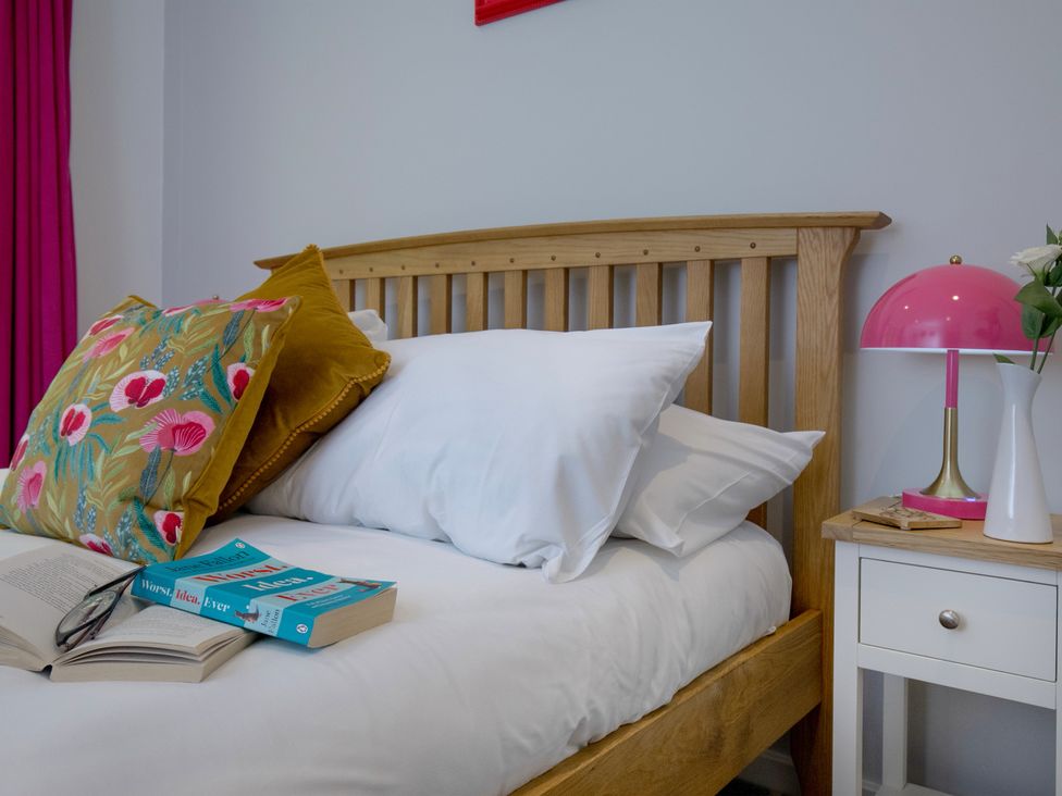 A bedroom with a wooden bed and bedside table at Mariners Retreat, 8 Pottery Cottages, Dartmouth