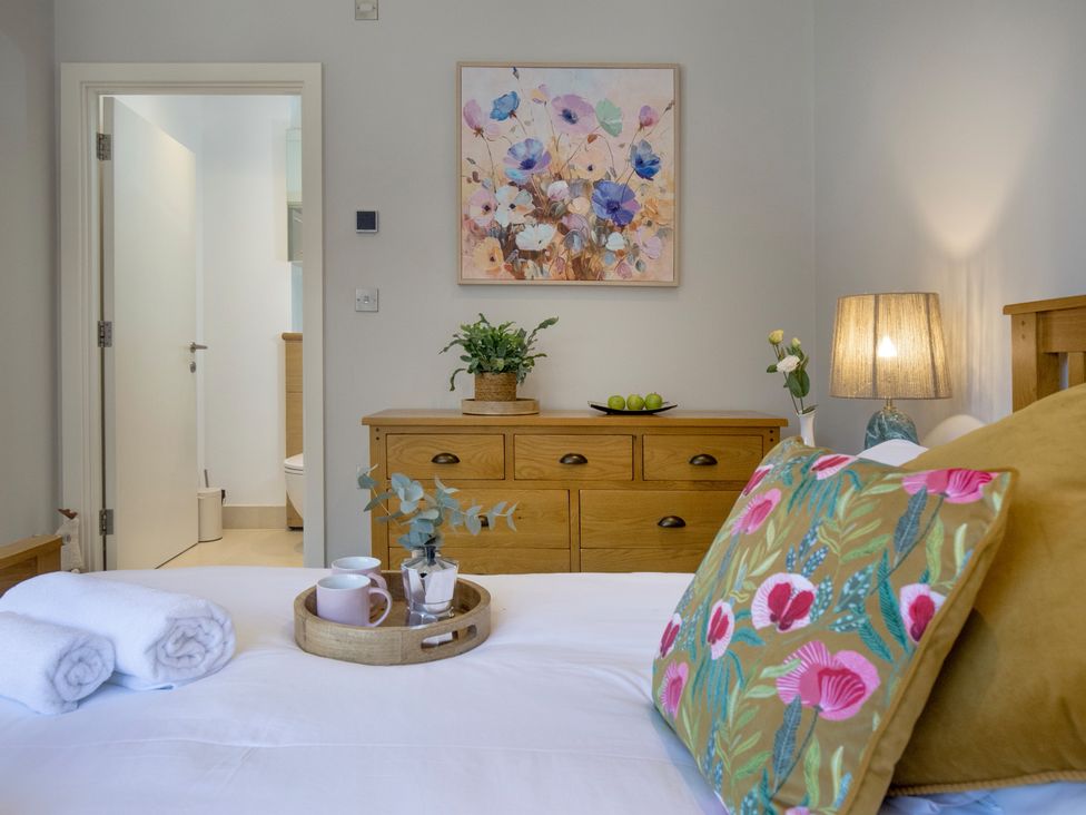 A bedroom with a bed and a wooden dresser at Mariners Retreat, 8 Pottery Cottages, Dartmouth