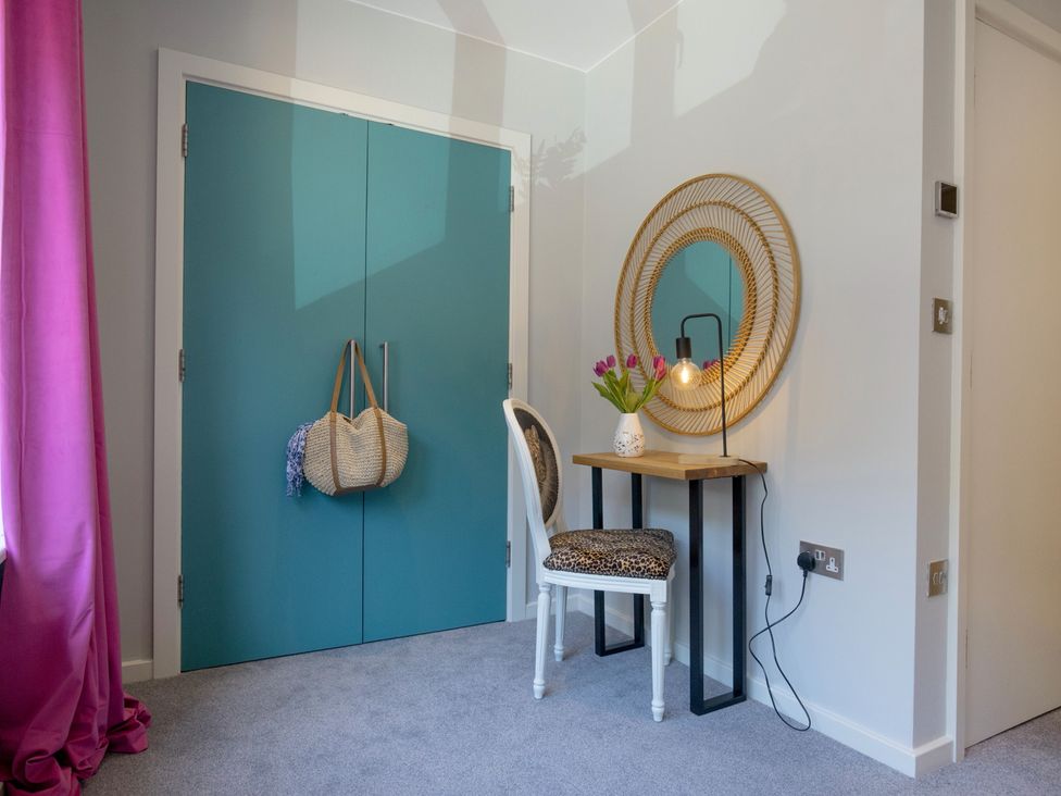 A corner with a table, a chair, and a mirror in a bedroom at Mariners Retreat, 8 Pottery Cottages, Dartmouth