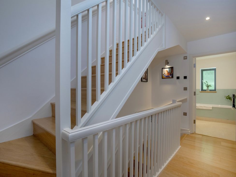 A hallway with staircase and bathroom door at Mariners Retreat, 8 Pottery Cottages Dartmouth