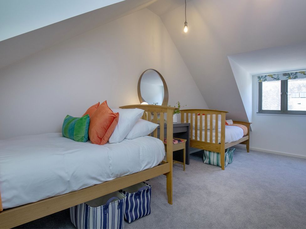 A bedroom with two beds and a mirror at Mariners Retreat, 8 Pottery Cottages, Dartmouth